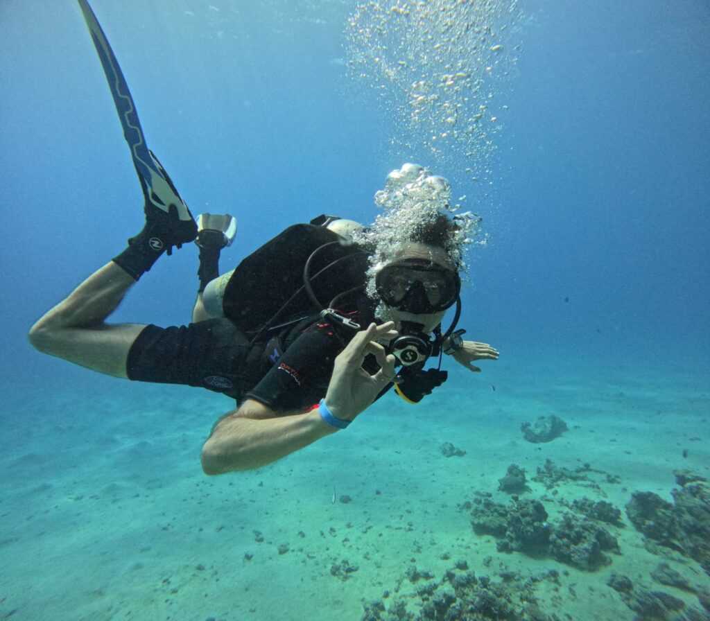 Bild eines Gerätetauchers im Meer. Es wirkt als wäre es sehr warm.